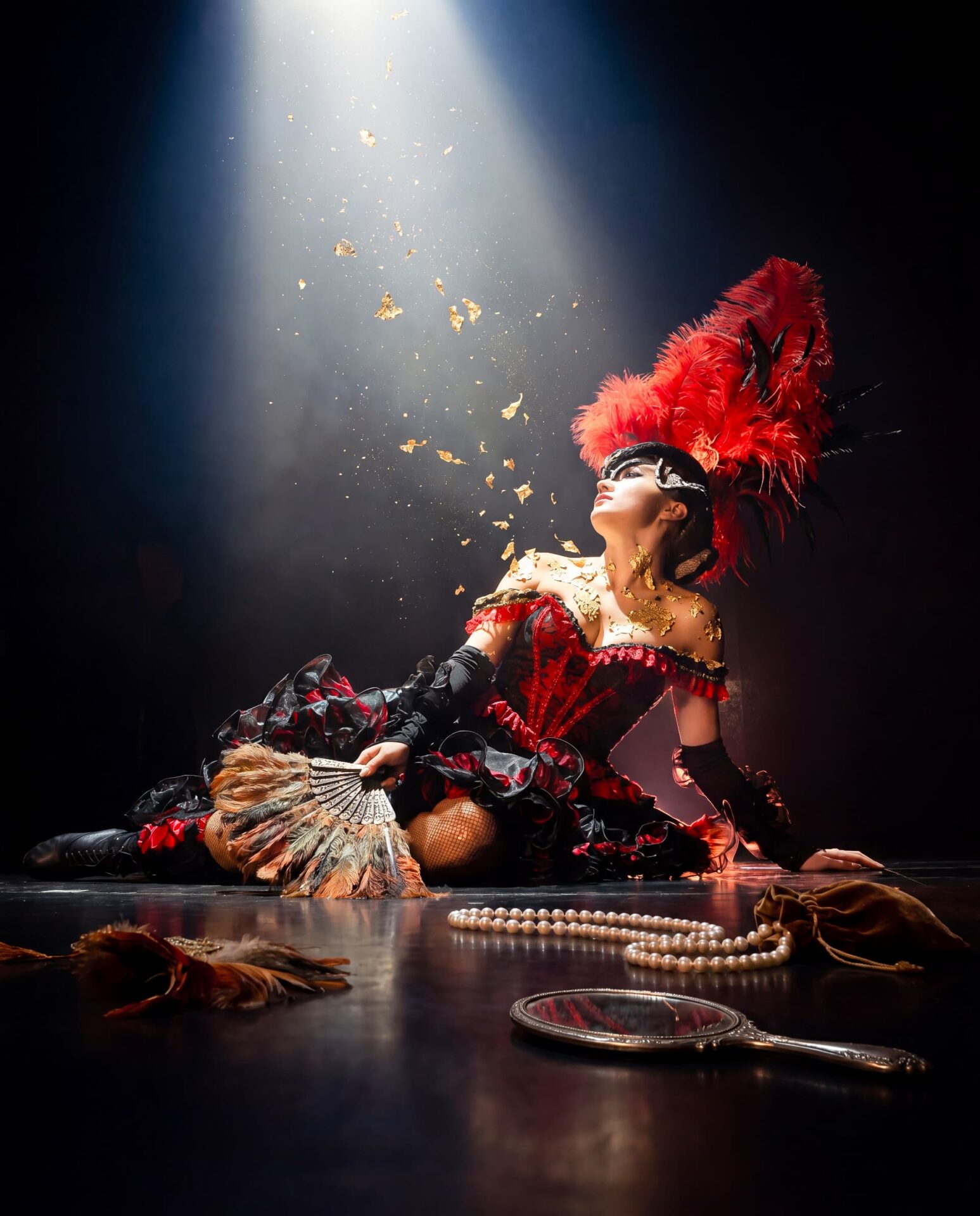Artiste de Métamorphose en costume rouge à plumes sous un projecteur, photographie officielle du Paradis des Sources.